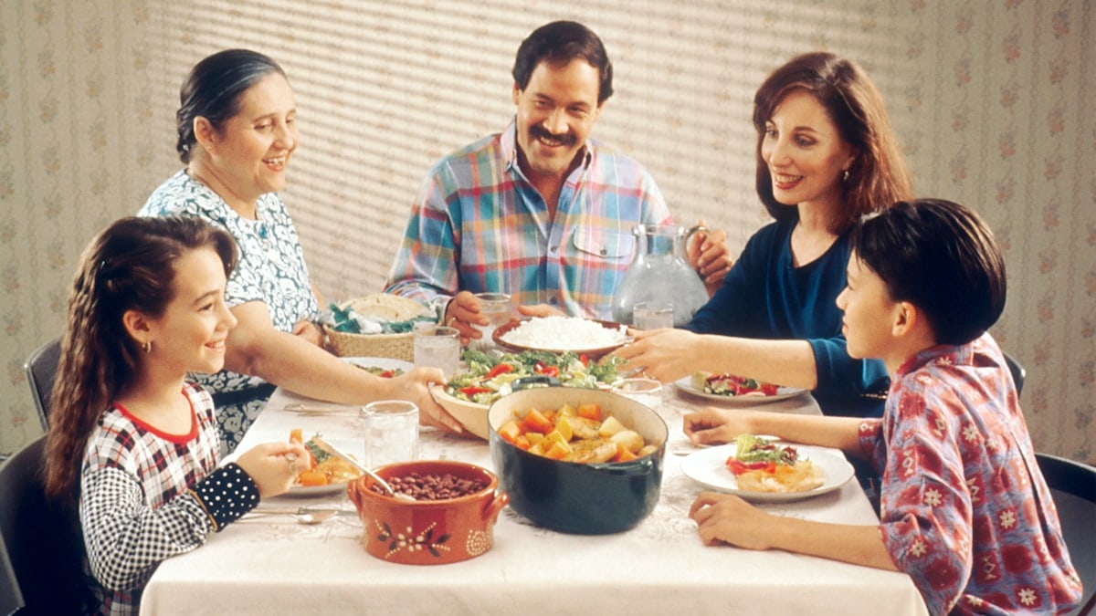 Family Eating Meal. A Hispanic family (male adult, two female adults, female child, and male child) enjoy a meal at the dinner table.